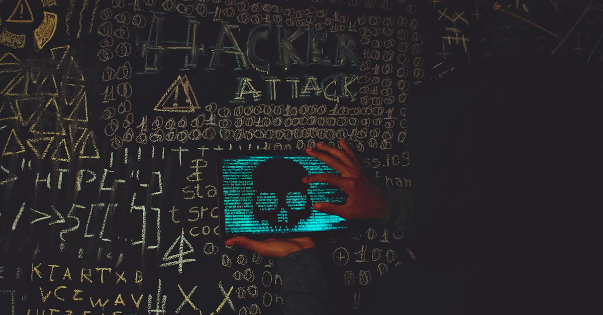 A hacker in a black hoodie using a tablet displaying a skull, surrounded by chalk symbols and 'Hacker Attack' text.
